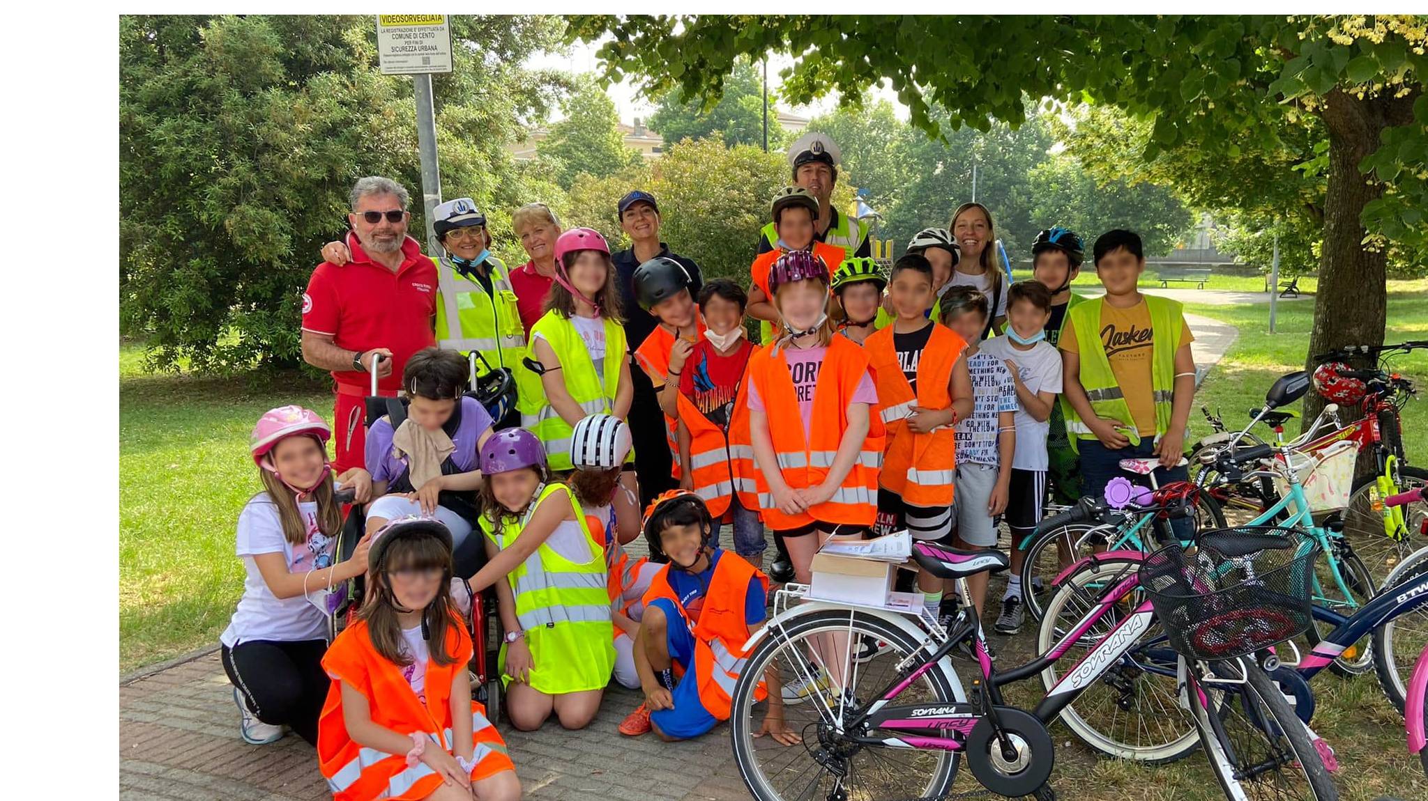 fotografia degli alunni e vigili in giardino con le biciclette