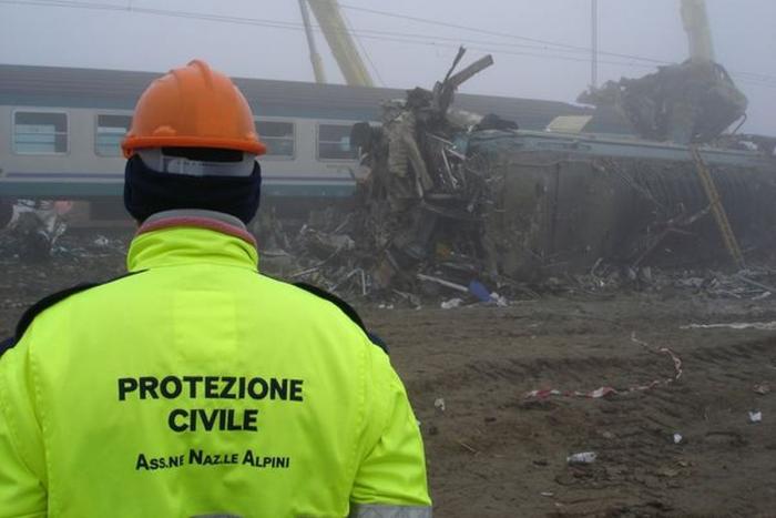volontario protezione civile di spalle con divisa gialla e scritta davanti al binario stazione Crevalcore strage