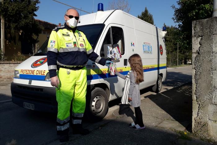 Signore della protezione civile dona uovo di pasqua a bambina