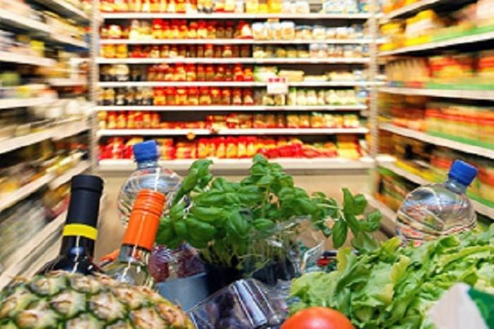carrello spesa ricolmo tra gli scaffali del supermercato 