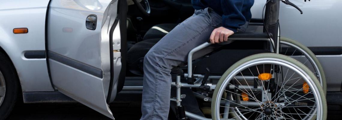 Persona che scende dalla carrozzina per salire in auto